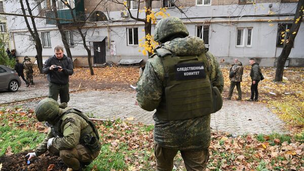 Сотрудники следственного комитета исследуют воронку, оставленную от снаряда после обстрела со стороны ВСУ в Донецке