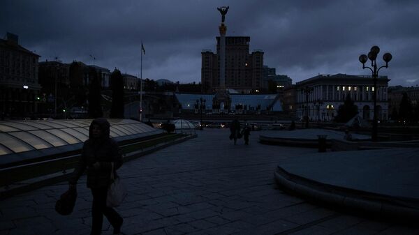 Люди идут по площади Независимости в Киеве в темное время суток. Архивное фото