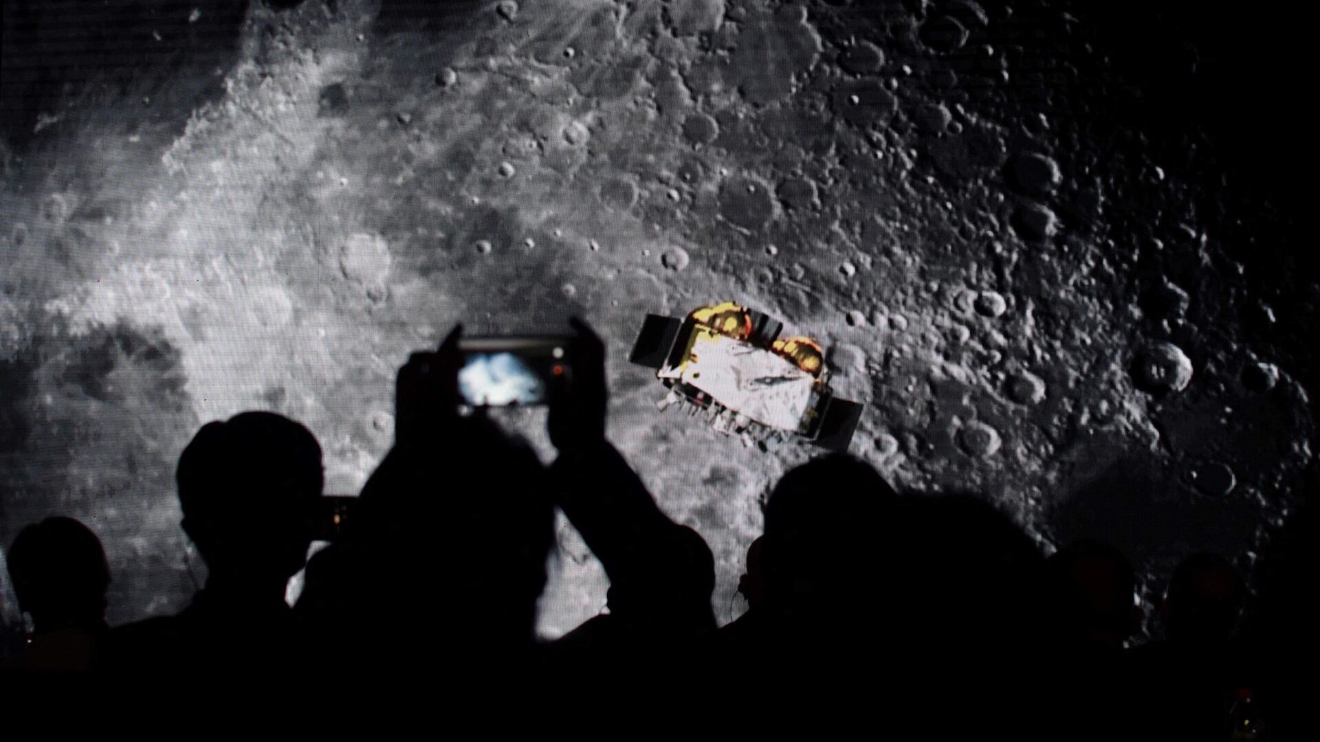 Зрители фотографируют экран с видео о китайском лунном зонде Чанъэ-5 на мероприятии, посвященном подробностям международного доступа к лунным образцам, собранным зондом, в Пекине - РИА Новости, 1920, 03.11.2022