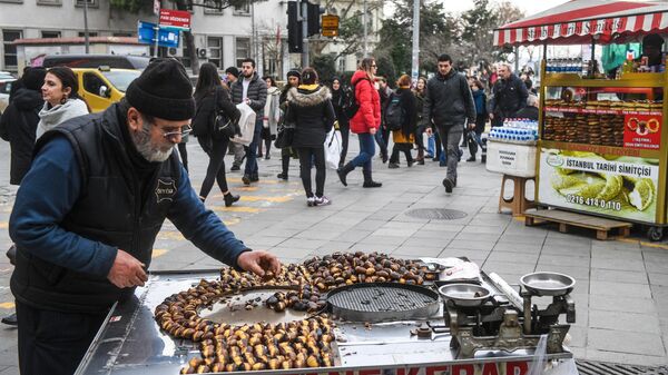 Мужчина продает жареные каштаны на одной из улиц Стамбула