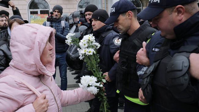 Сотрудники полиции и участница акции протеста оппозиции в Кишиневе