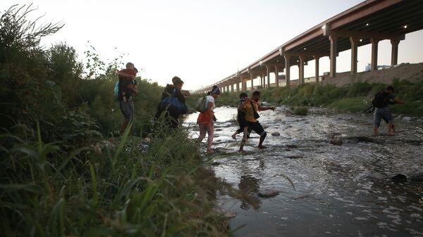 Мигранты переправляются через реку Рио-Браво на границе США с Мексикой