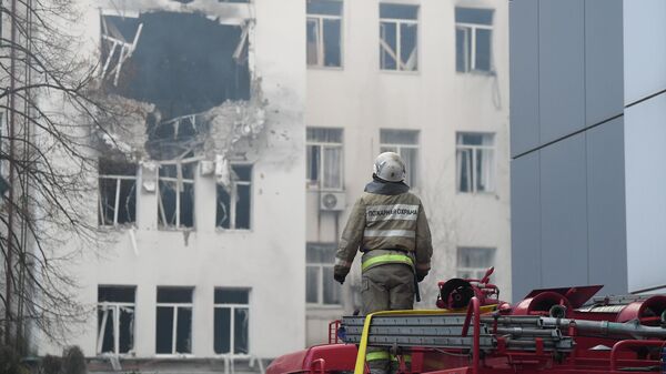 Сотрудник пожарно-спасательного центра у дома, пострадавшего в результате обстрела ВСУ в Донецке