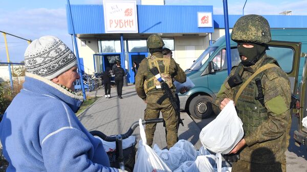 Мобилизованный военнослужащий РФ передает гуманитарную помощь местной женщине в городе Каменке-Днепровской Запорожской области