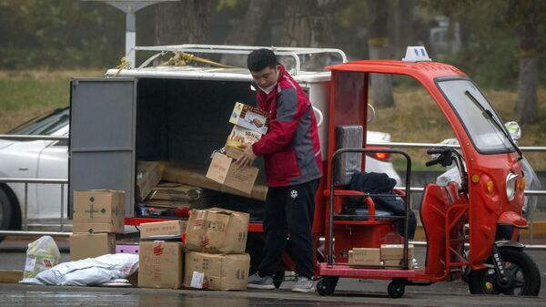 Курьер по доставке сортирует посылки на улице в Пекине