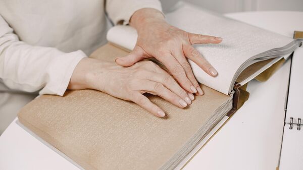 Женщина читает книгу при помощи шрифта Брайля. Архивное фото