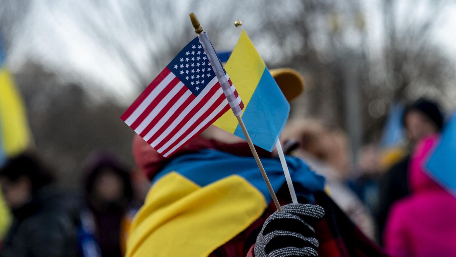 Человек держит флаги США и Украины перед Белым домом в Вашингтоне - РИА Новости, 1920, 18.03.2023