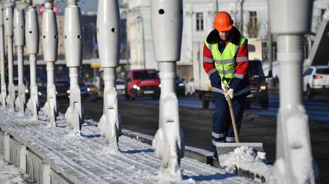 Сотрудник коммунальных служб чистит снег на Крымском мосту в Москве. 16 ноября 2022