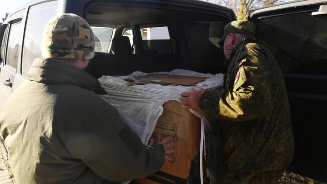 Военнослужащие ВС РФ разгружают гуманитарную помощь, привезенную журналистами РИА Новости, в Запорожской области