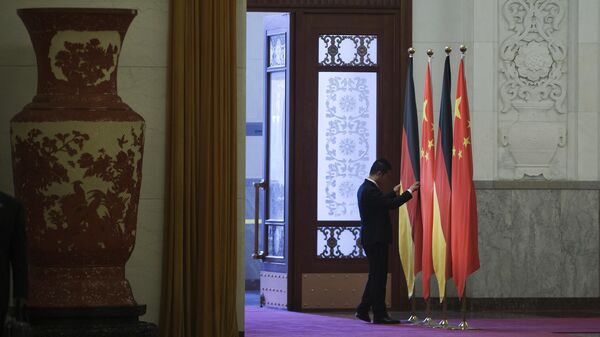 Работник поправляет флаги Германии и Китая в Доме народных собраний в Пекине