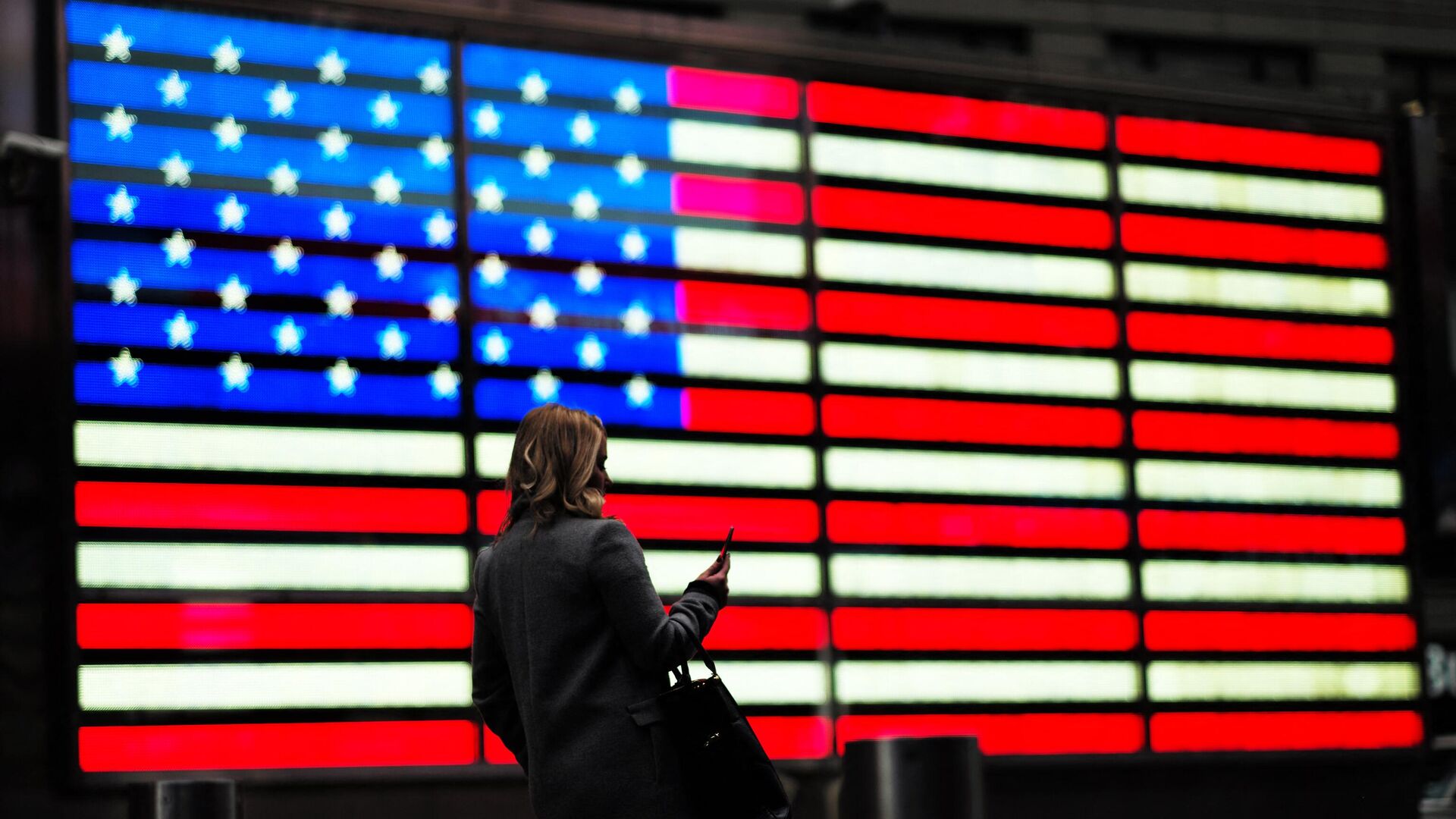 Женщина проходит мимо флага США на Таймс-сквер в Нью-Йорке - РИА Новости, 1920, 21.11.2022