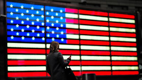 Женщина проходит мимо флага США на Таймс-сквер в Нью-Йорке