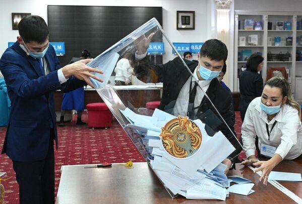 Сотрудники избирательной комиссии на одном из избирательных участков в Астане достают бюллетени из урны для подсчета голосов по итогам внеочередных выборов президента Казахстана