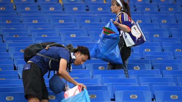 Болельщики сборной Японии убирают мусор после окончания матча 1/8 финала чемпионата мира по футболу между сборными Бельгии и Японии.