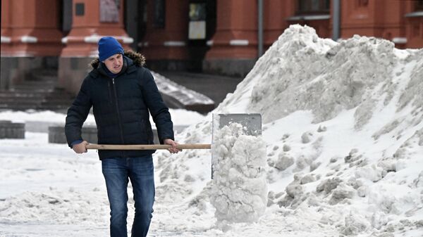 Мужчина чистит дорогу от снега в Москве