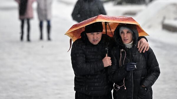 Люди идут под зонтом во время ледяного дождя в Москве