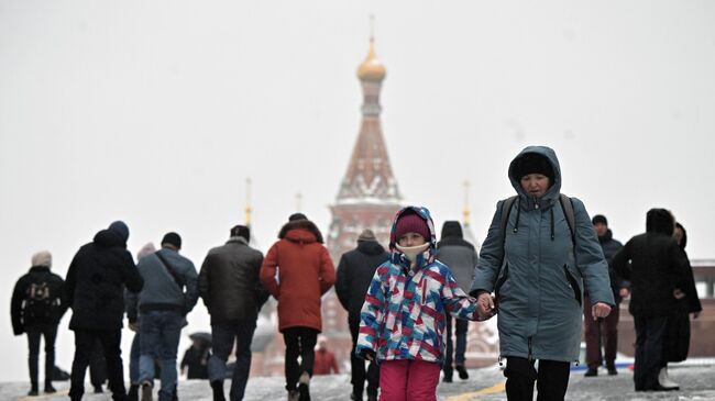 Люди идут по Красной площади во время ледяного дождя в Москве