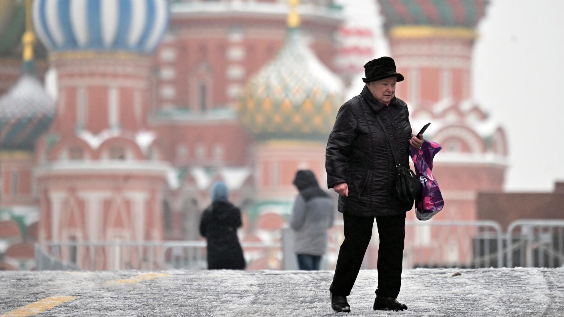Пожилая женщина на Красной площади во время ледяного дождя в Москве - РИА Новости, 1920, 22.11.2022