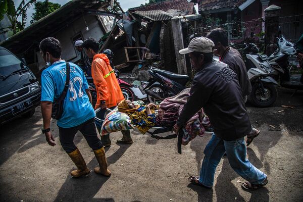 Жители деревни несут раненого после землетрясения в провинции Западная Ява, Индонезия