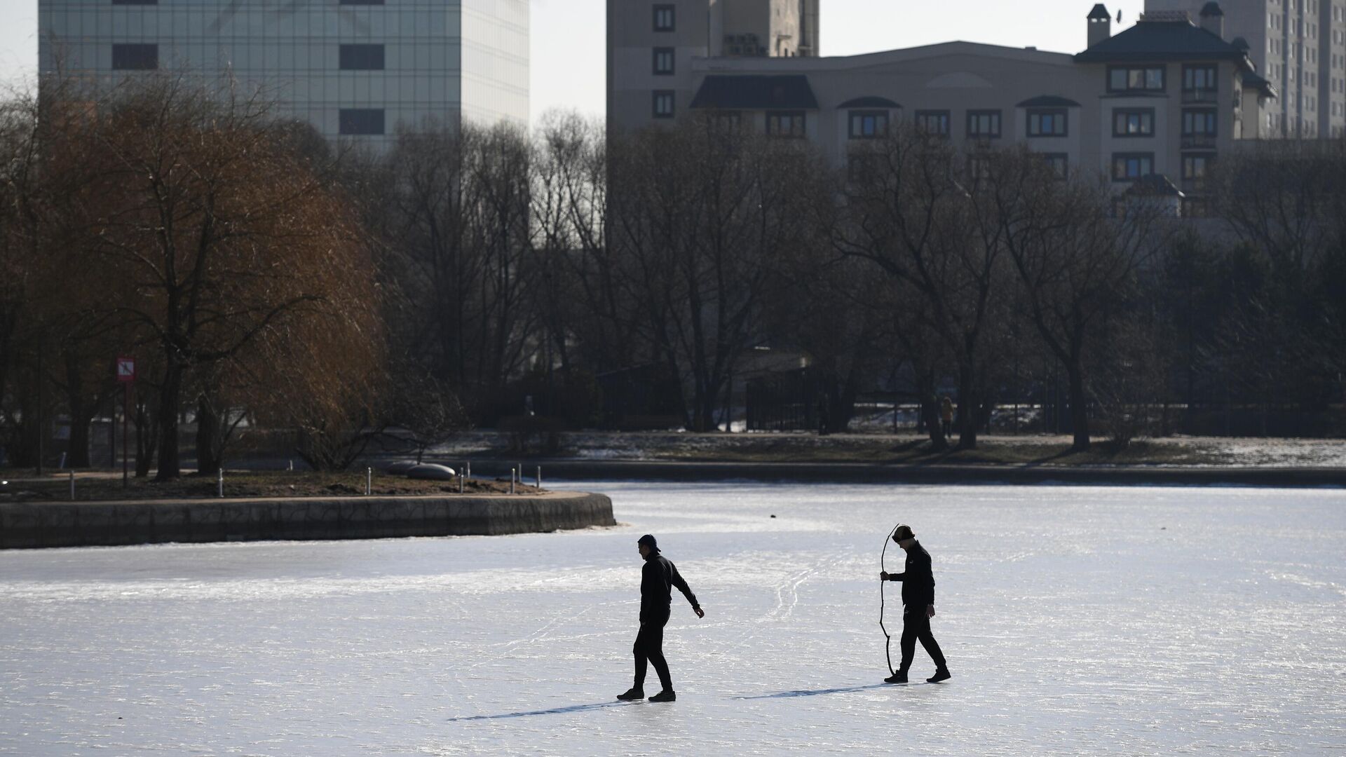 Мужчины ходят по замерзшему пруду в парке Дружбы в Москве - РИА Новости, 1920, 23.11.2022