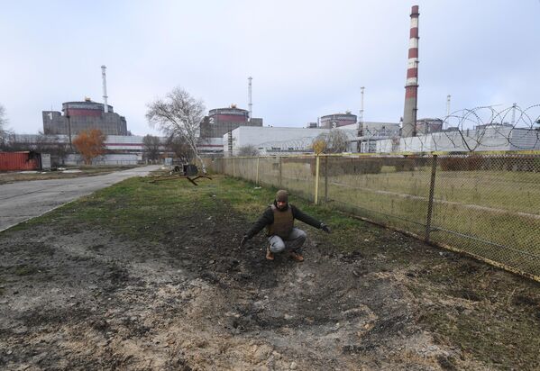 Сотрудник Росэнергоатома у воронки от разорвавшегося снаряда на территории Запорожской атомной электростанции после недавних обстрелов со стороны ВСУ
