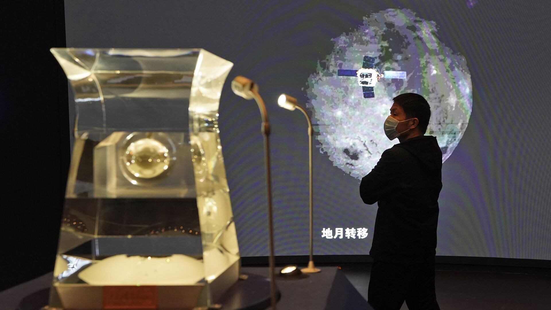 Посетитель Национального музея смотрит на выставку образцов лунных пород, извлеченных с Луны китайским лунным модулем Чанъэ-5 в Пекине. - РИА Новости, 1920, 24.11.2022