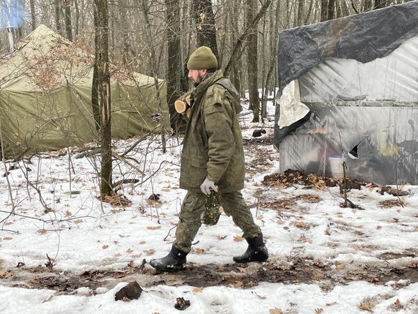 Боец на позициях артиллеристов несет дрова в полевую баню Боец на позициях артиллеристов несет дрова в полевую баню