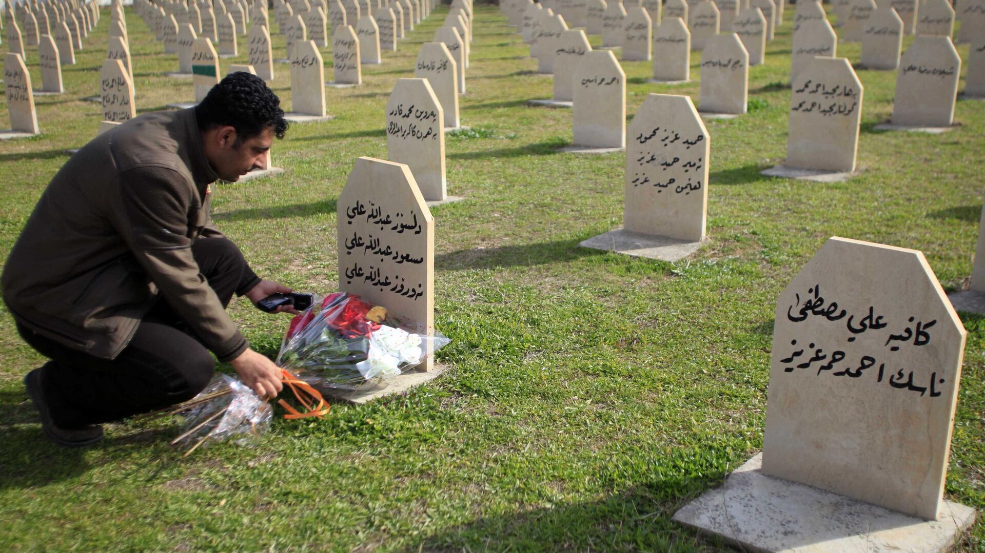 Мужчина возлагает цветы на могилу жертвы химической атаки 1988 года в городе Халабджа на севере Ирака - РИА Новости, 1920, 30.11.2023