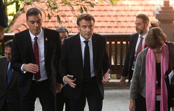 Президент Франции Эмманюэль Макрон (справа) и премьер-министр Испании Педро Санчес покидают Grand Hyatt Bali, где проводилось экстренное совещание лидеров стран G7