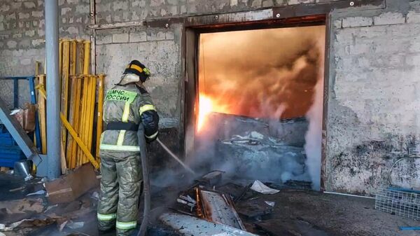 Сотрудник МЧС РФ тушит пожар в цехе по производству пластиковой тары в двухэтажном здании на улице Самарской в Волгограде
