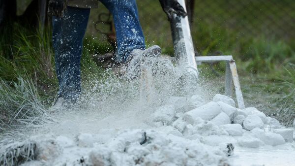 Рабочий выбивает грунт из бура во время бурения скважины для добычи воды
