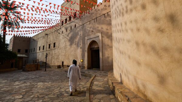 Мужчина идет мимо стен Форта Низва в Омане