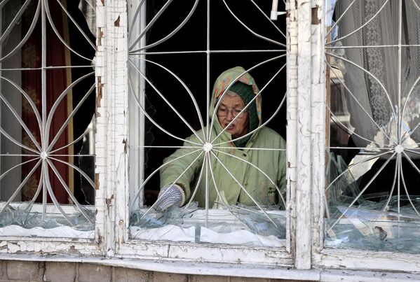 Женщина убирает осколки стекла окон, поврежденных в результате обстрелов со стороны ВСУ Киевского района Донецка