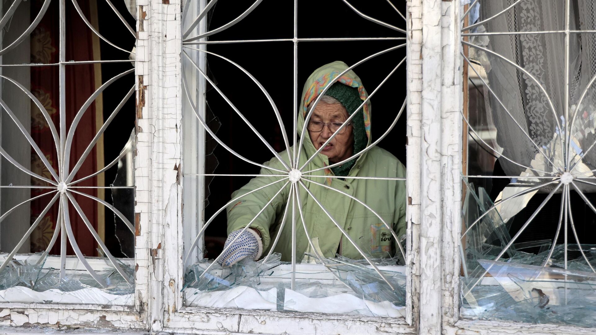 Женщина убирает осколки стекла окон, поврежденных в результате обстрелов со стороны ВСУ Киевского района Донецка - РИА Новости, 1920, 02.12.2022