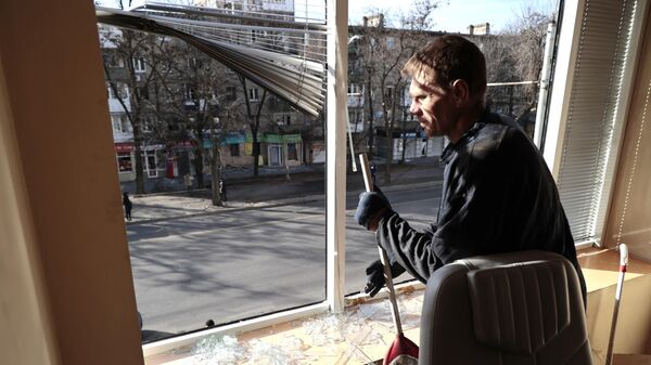 Мужчина убирает осколки стекла в офисном помещении, поврежденном в результате обстрелов со стороны ВСУ Киевского района Донецка