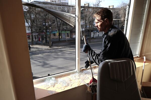 Мужчина убирает осколки стекла в офисном помещении, поврежденном в результате обстрелов со стороны ВСУ Киевского района Донецка