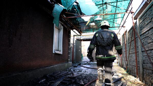 Сотрудник МЧС ДНР работает на месте пожара в жилом доме в Киевском районе Донецка, загоревшемся в результате обстрела ВСУ