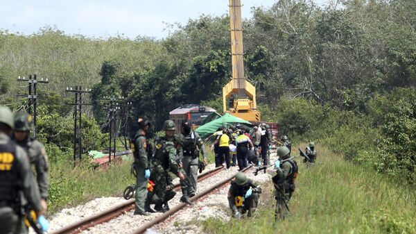 Чиновники тайской службы по обезвреживанию боеприпасов осматривают участок железнодорожного пути, поврежденный взрывом бомбы, в провинции Сонгкхла, южный Таиланд