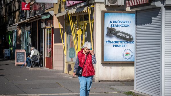 Женщина проходит мимо плаката с надписью Нас наказывают санкции Брюсселя на улице Будапешта, Венгрия