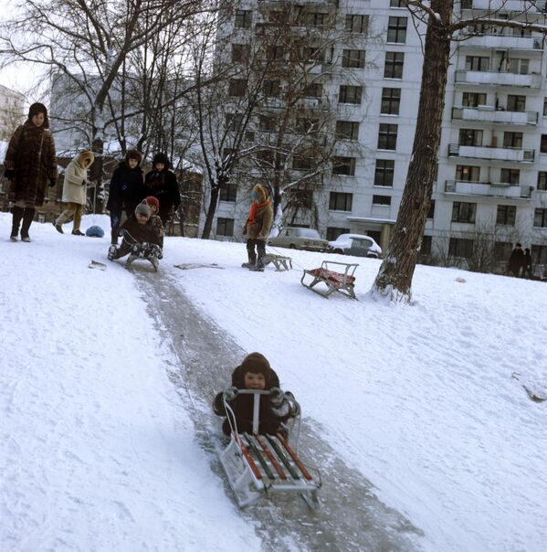 Дети катаются на санках с ледяной горки