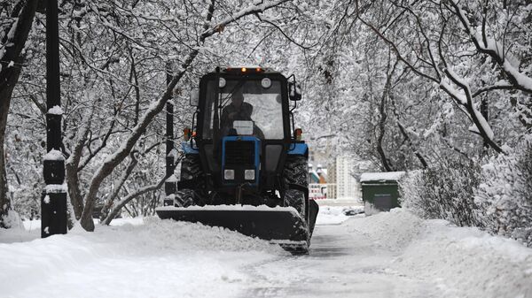 Трактор коммунальной службы убирает снег в Москве