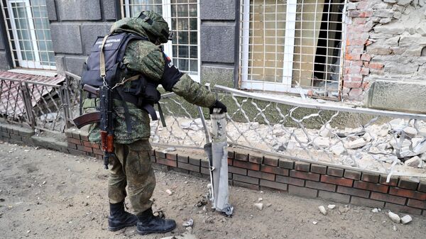 Представитель СК РФ фиксирует фрагмент разорвавшегося снаряда от РСЗО Град в Донецке после обстрела со стороны ВСУ