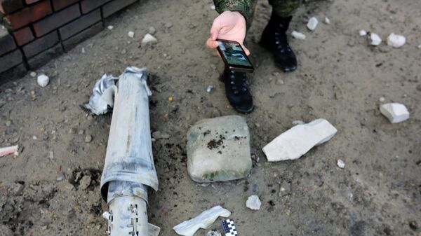 Представитель СК РФ фиксирует фрагмент разорвавшегося снаряда от РСЗО Град в Донецке
