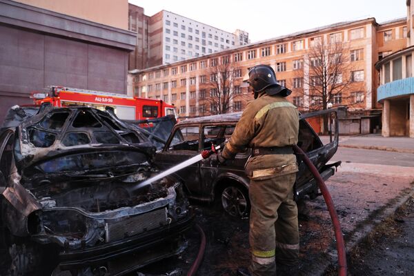 Пожарный тушит машину, загоревшуюся в результате обстрела Донецка со стороны ВСУ