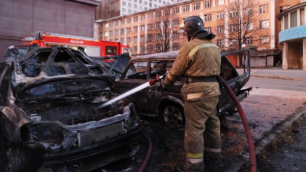 Пожарный тушит машину, загоревшуюся в результате обстрела Донецка со стороны ВСУ