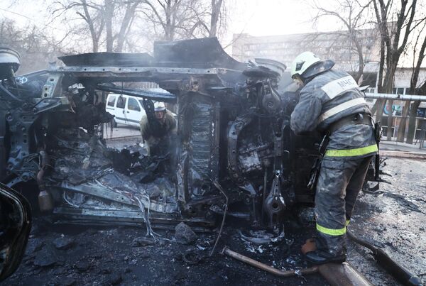 Сотрудники МЧС осматривают машину, загоревшуюся в результате обстрела Донецка со стороны ВСУ