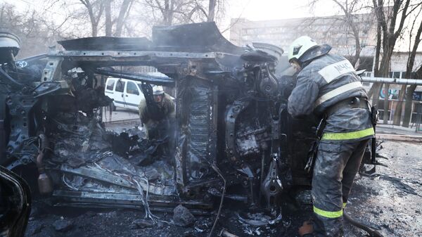 Сотрудники МЧС осматривают машину, загоревшуюся в результате обстрела Донецка со стороны ВСУ