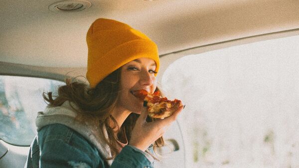 Девушка ест пиццу в автомобиле 