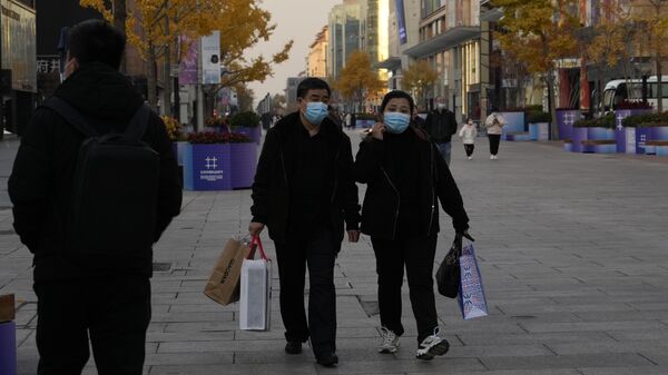 Прохожие в масках на торговой улице Ванфуцзин в Пекине