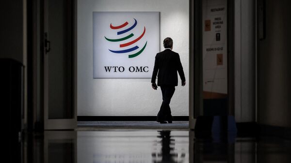 Мужчина проходит мимо вывески Всемирной торговой организации в ее штаб-квартире в Женеве